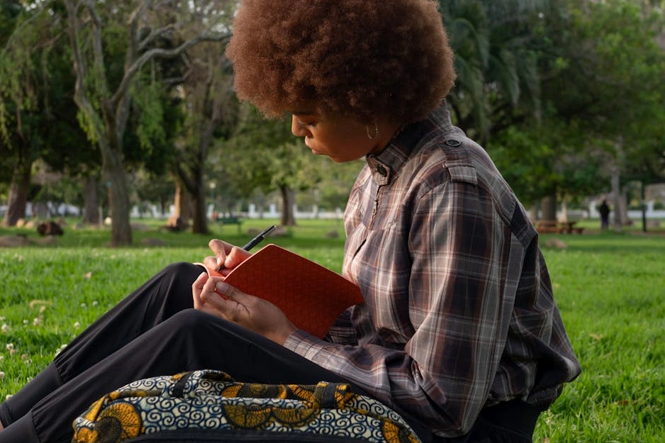 A person carefully making notes in a journal with astronomical charts in the background.
